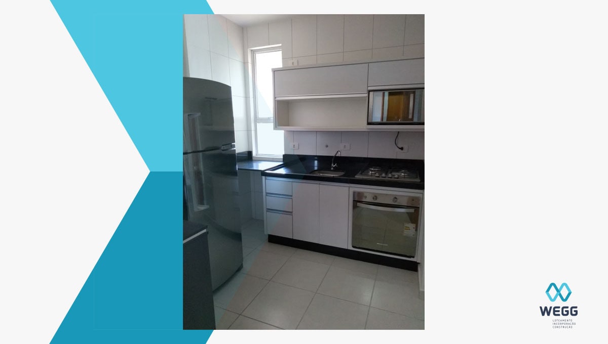 The kitchen features modern appliances, including a refrigerator, stove, and oven. A sleek black countertop complements the white cabinetry, while a window allows natural light to brighten the space. Ample storage is provided by upper and lower cabinets.