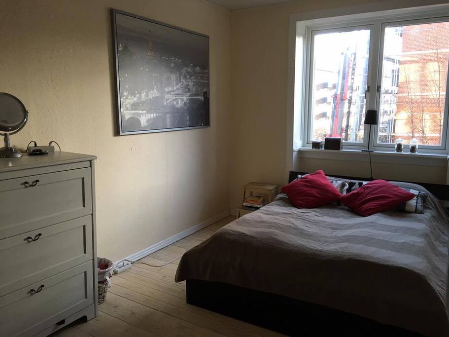 A bright bedroom with a comfortable double bed, dresser with a mirror and a closet