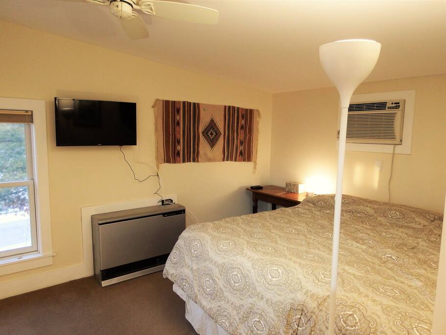 Sleeping area with king bed, smart TV on full-motion wall mount so visible in bed or in kitchen