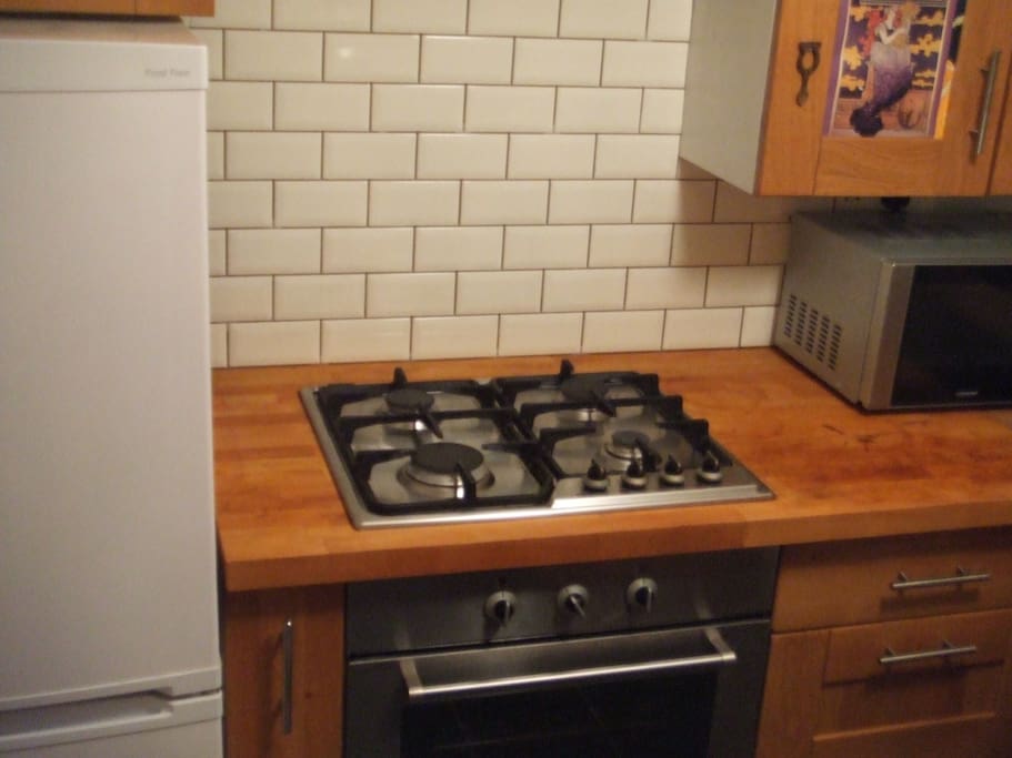 Gas cooker and electric oven, wood counter tops, all nicely tiled.