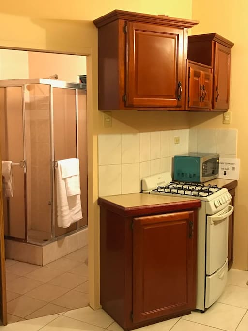 Entrance to bathroom , kitchen area showing cupboards, stove and microwave