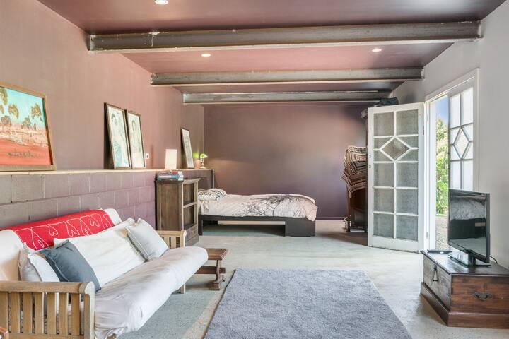 Estudio independiente en la planta baja con cama tamaño queen, sofá cama, cocina pequeña, TV y baño privado.