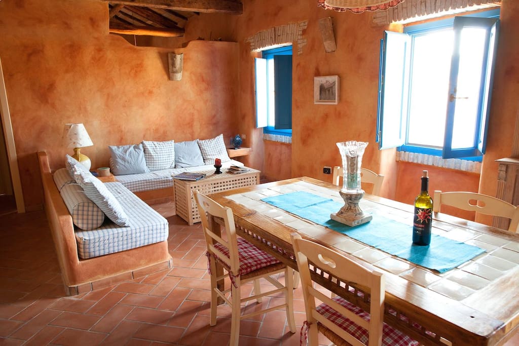 Casa Teulada - Dining table and stone sofa beds - una sala rustica con divani letto in muratura
