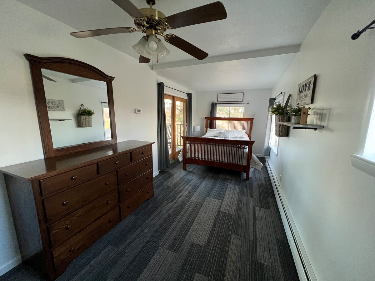 前卧室，配有标准双人床和露台门，可俯瞰河流