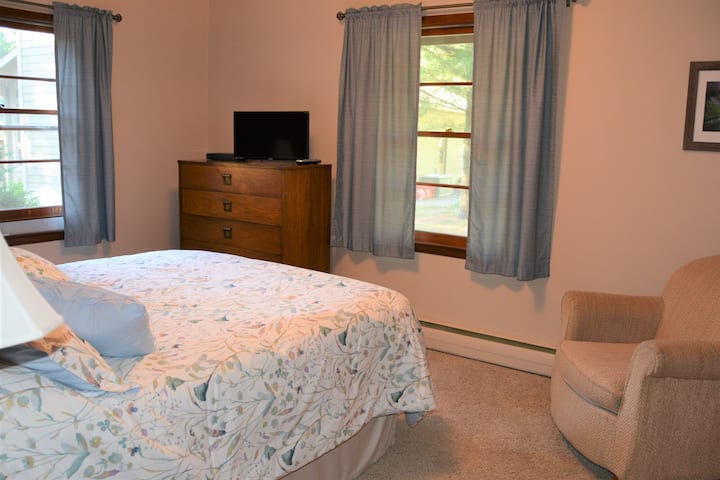 חדר שינה עם מיטת קווין סייז, שידה, טלוויזיה ומיזוג אוויר.