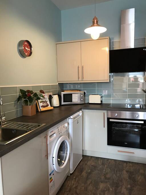 Modern kitchen with hob, oven microwave, washing machine and all pots pans you need to make a nice meal