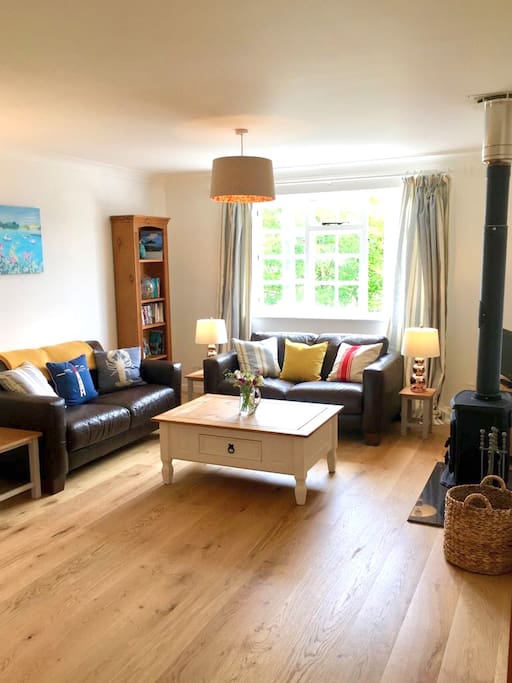 Light, airy living room with comfy sofas and a wood burning stove