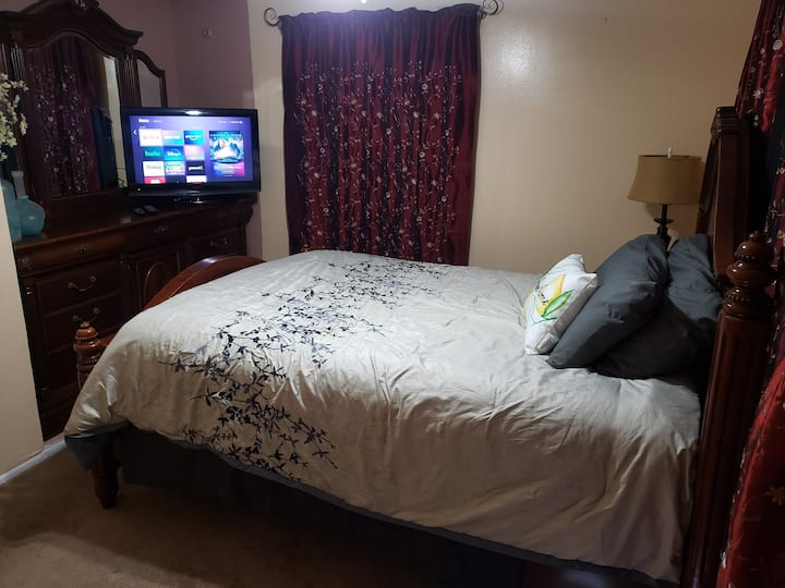 Esta es una habitación alegre con una cama queen size, TV Roku de 32 pulgadas, wifi, mesa con una silla es buena para poner una computadora, un tocador con espejo y un armario con una percha. El baño compartido está muy cerca de solo unos pasos. Sala de estar compartida y cocina compartida