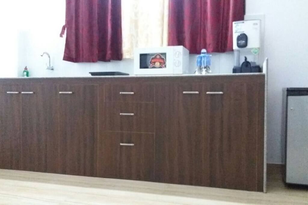 Kitchenette with Microwave, Induction Stove, Fridge, Water Filter and utensils provided in storage cabinet