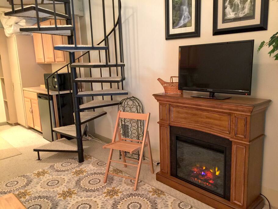 View of the stairs, fireplace, dishwasher, microwave and kitchen.