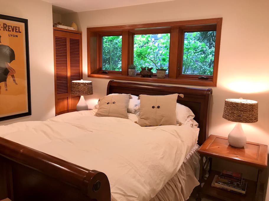 Queen sleigh bed with windows that open to the side garden and sounds of a water feature.