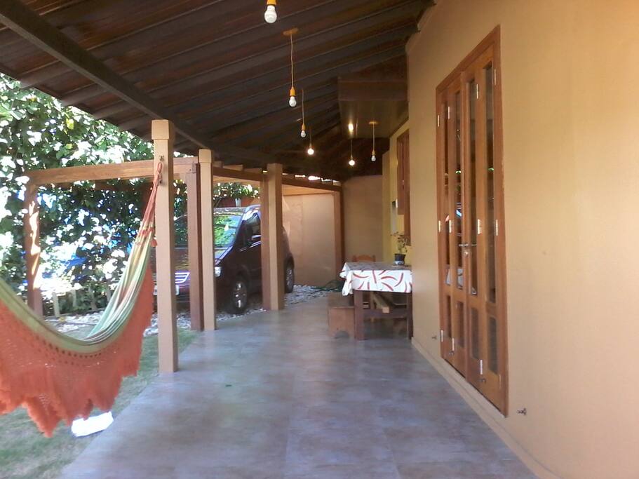 Ampla varanda com churrasqueira, garagem e acesso a sala.