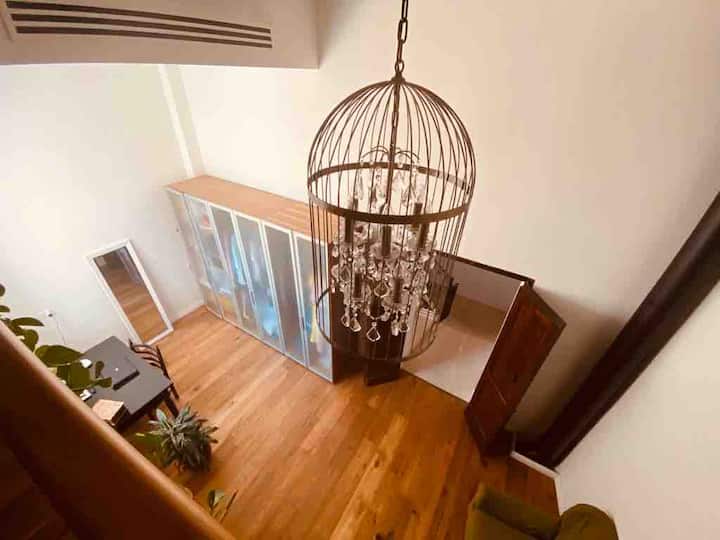 卧室内设有舒适的起居区，配有硬木地板和裸露的原木梁、面向法式大窗户的办公桌和大衣柜。