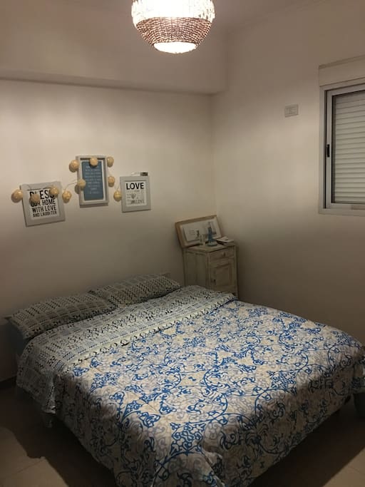 Dormitorio con somier 2 plazas, mueble de guardado y ventana con vista a la ciudad