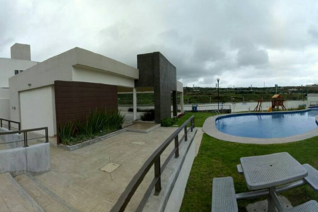 Area común del condominio, cuenta con alberca, palapa, juegos para niños y asador
