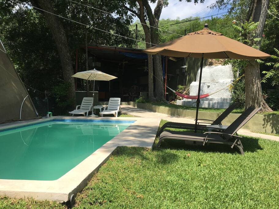 Vista de la alberca con jacuzzi y calefacción; camastros con sombrillas a la orilla