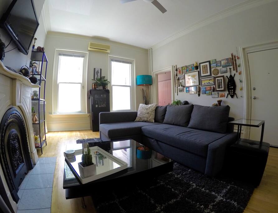 Living room with pullout sofa, marble fireplace, ceiling fan, built in air conditioner, and flatscreen TV