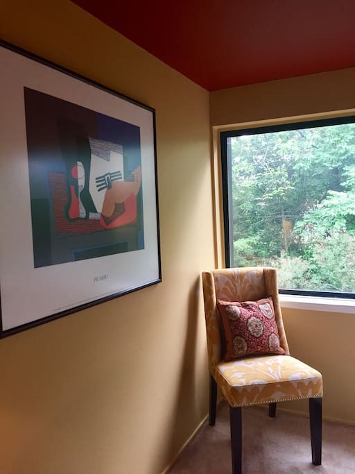 A comfortable upholstered chair and a Picasso art print.