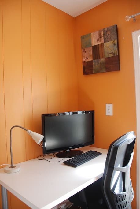 Desk with flat screen monitor, lamp, and external keyboard and mouse makes for a very comfortable work space from home.