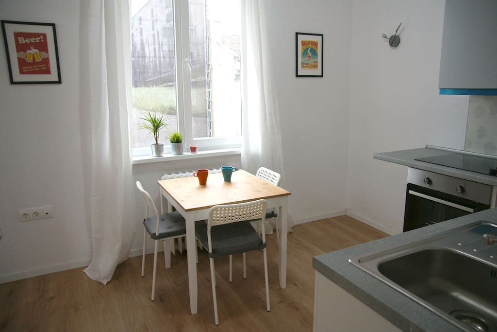 Kitchen with a small dining table, fridge, oven, hotplate, coffee machine, toaster