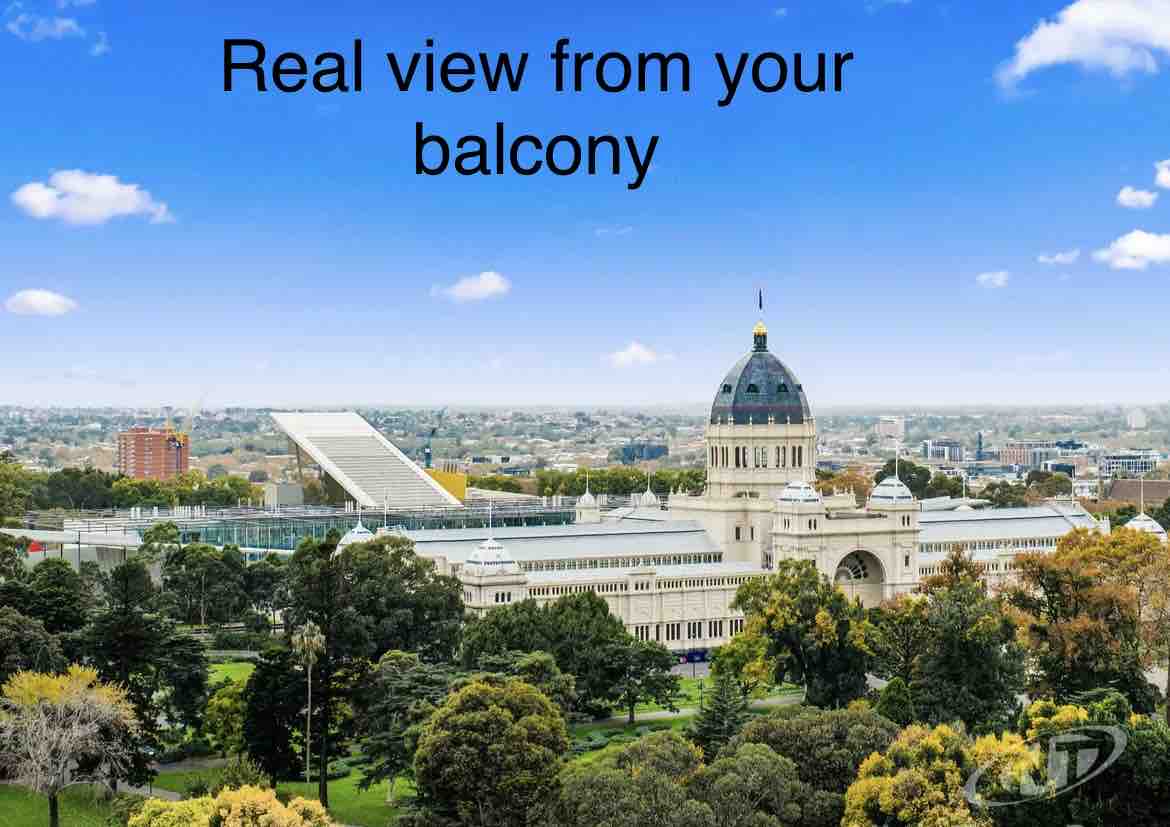 A scenic view showcases green trees and landscaped gardens in the foreground, with urban buildings and a notable dome structure in the background. The sky is bright with a few fluffy clouds, creating a picturesque backdrop.