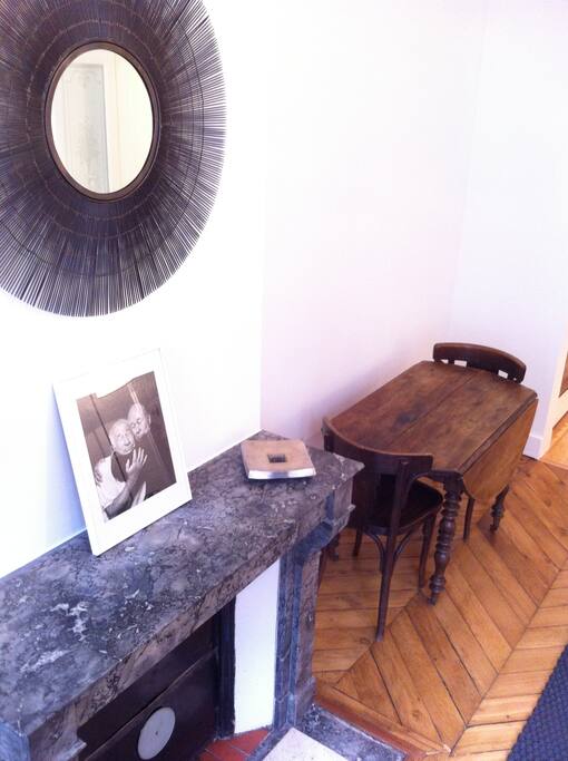 Bright salon with dining table, lovely fireplace details.