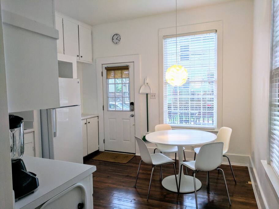 The kitchen viewed from the living room. A large cafe table and chairs serve as the main dining area. The kitchen also features two large wooden windows and is accessible to the back door, which is where guests will enter upon arriving.