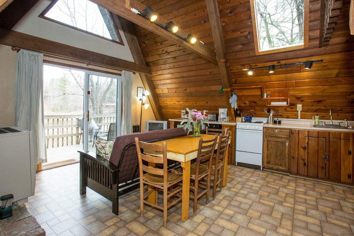 Spacious living room with skylights and sliding glass door opens up on deck and overlooks beautiful lake.