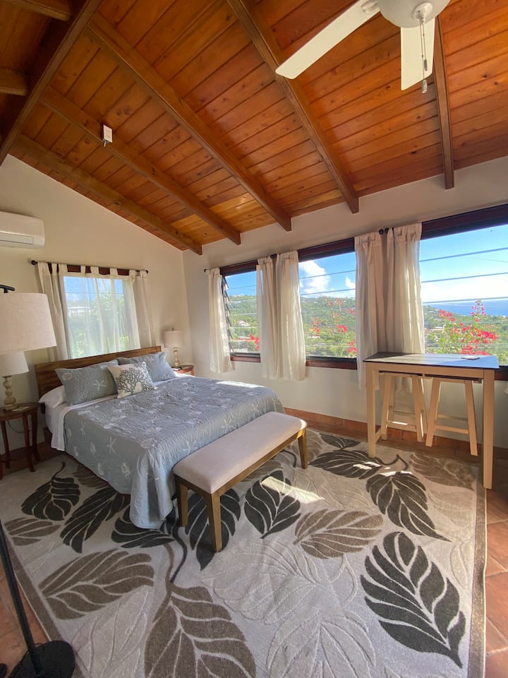 تقع غرفة النوم السادسة في الكوخ مع إطلالة رائعة على المحيط وزهور خارج نافذتك.