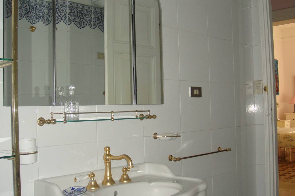 Particolare bagno privato con ampia finestra, vasca, doccia, asciugacapelli, sciampo e bagno schiuma.