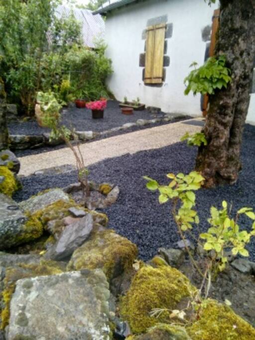 Devant de porte ombragée et fleuri, avec table et chaise pour déjeuner dehors au grand air