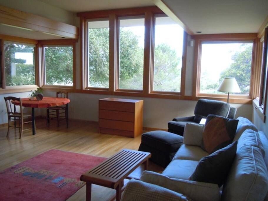 Beautiful living room, full of natural light, natural solid wood furniture, and super comfortable upholstered sofa and chair.