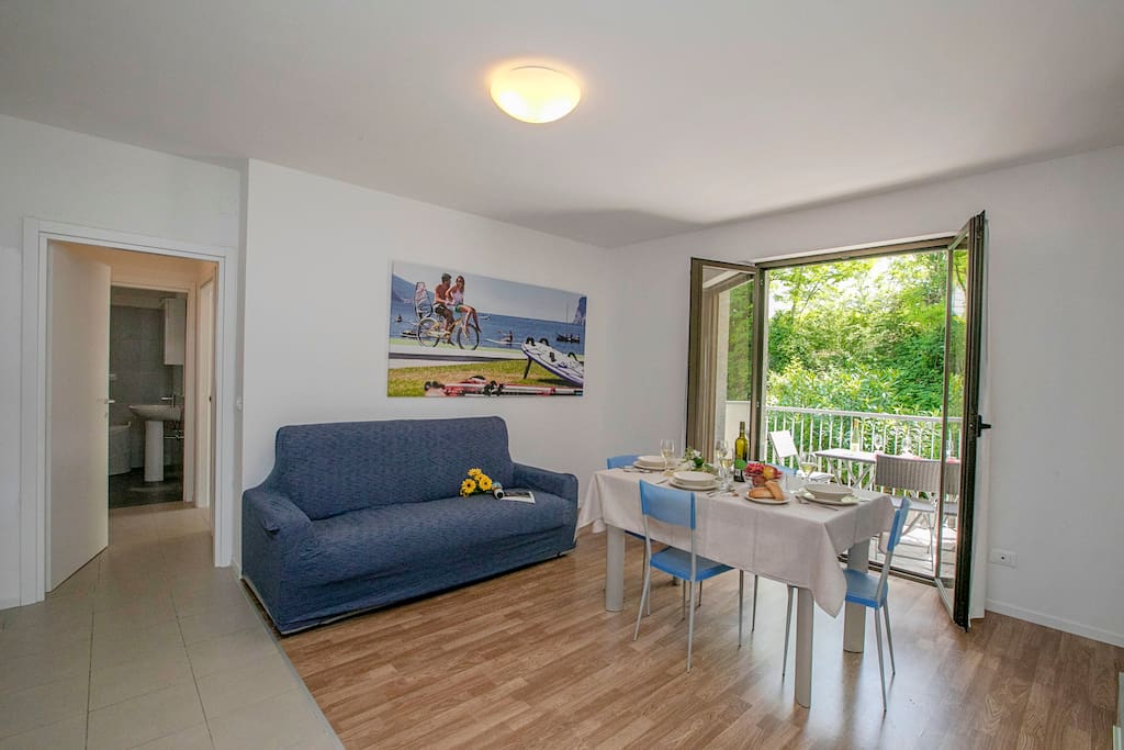 The bright living room with sleeping sofa, dining set and entranc to the terrace