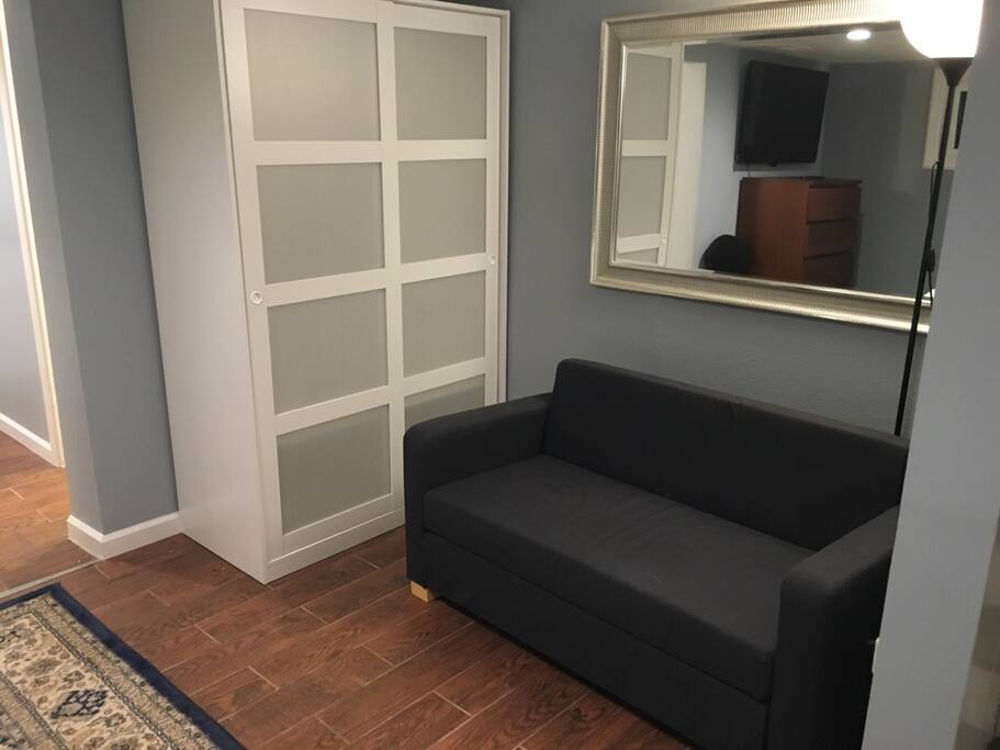 Wardrobe with clothes hanger bar and couch.