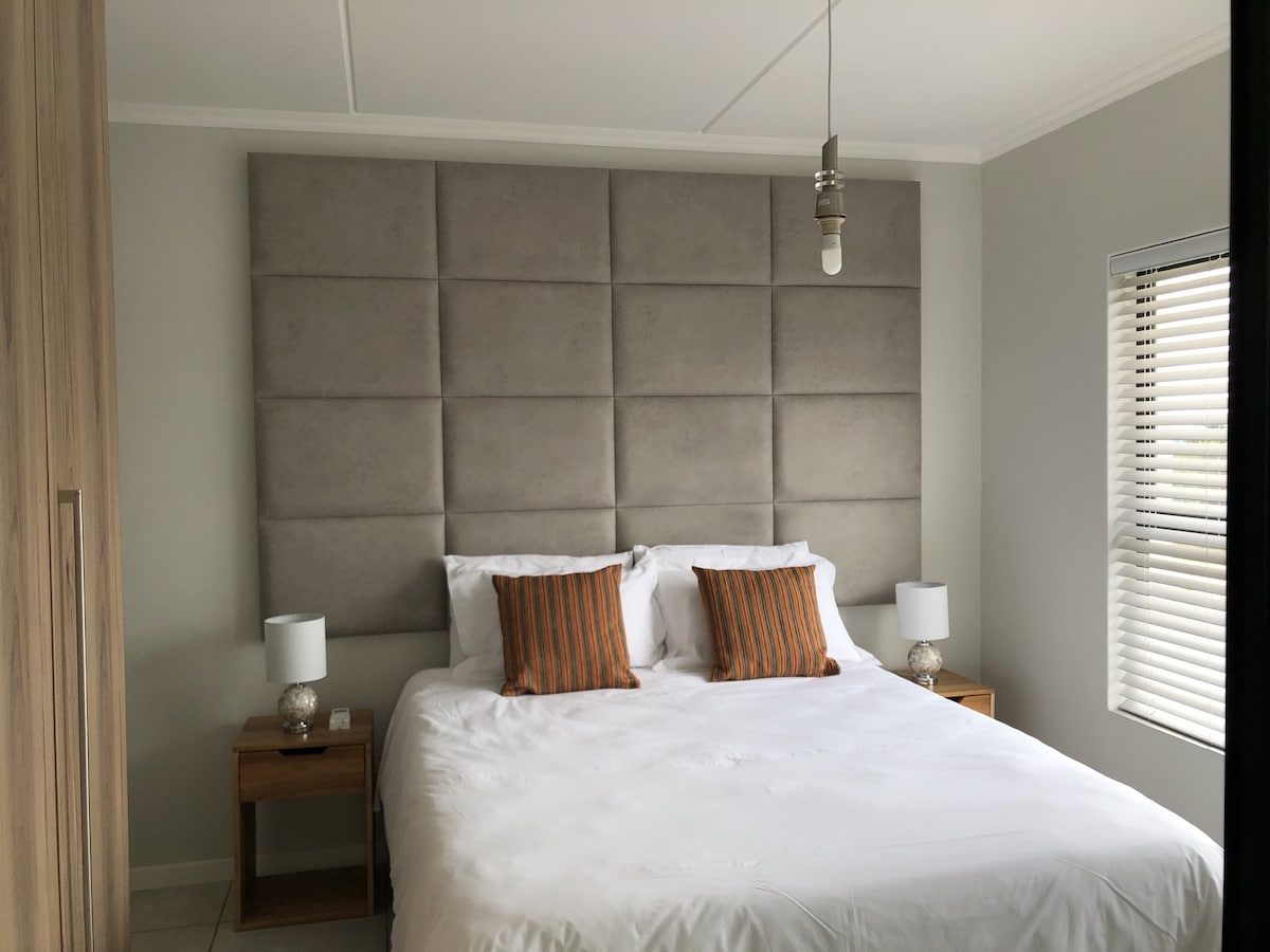 Hlavná spálňa s pohodlnou manželskou posteľou veľkosti XL, 2 bočnými lampami, 2 chodníkmi a šatníkom.