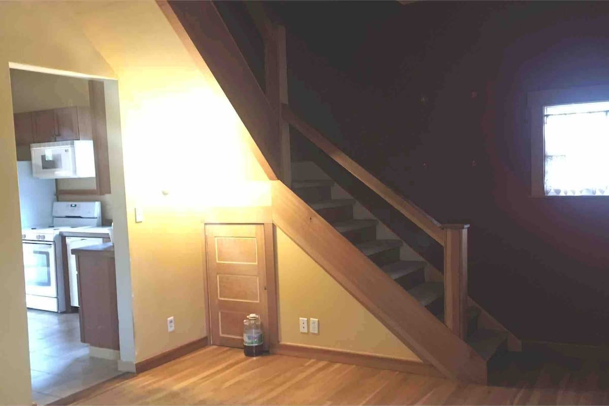 Schodisko v obývacej izbe do priestoru na spanie na poschodí a miestnosti s dennou posteľou a písacím stolom