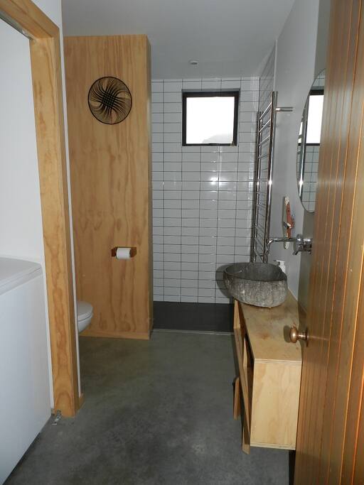 Toilet, shower and washing machine. Stone sink.