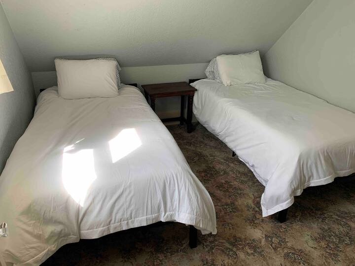 An upstairs bedroom with two twin beds each with a memory foam mattress.