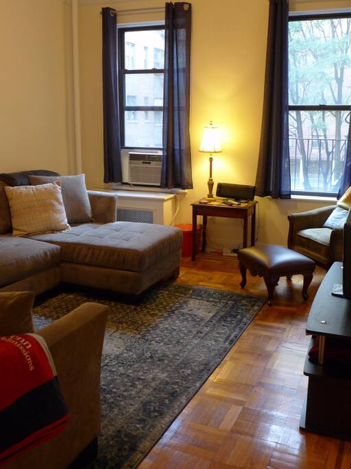 The sunny and inviting living area, with a massive sectional couch and TV.