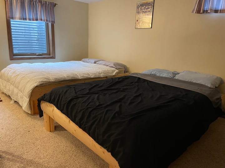 מציג 2 מיטות קווין סייז/מלאות של ארבע המיטות בחדר השינה בקומה התחתונה עם חלונות יציאה