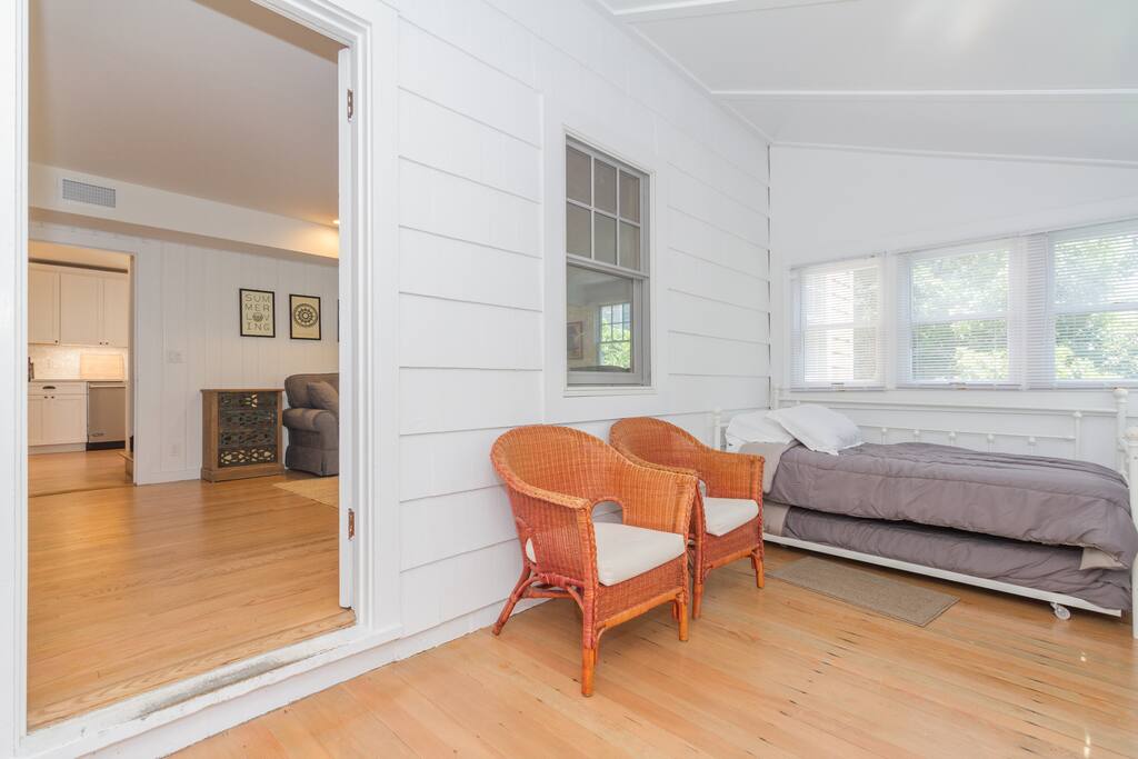 The enclosed sleeping porch has a twin daybed with a trundle, 2 additional cushioned chairs, and a built in bench seat.