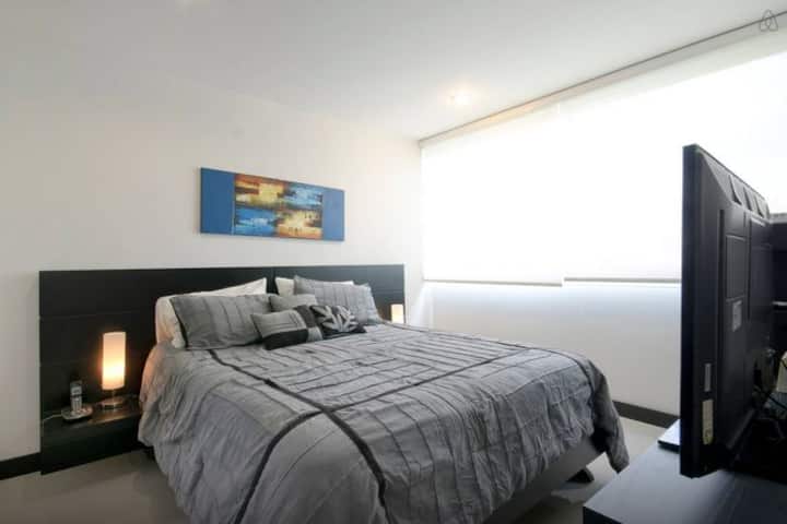 A serene bedroom featuring a plush queen-size bed and flat-screen TV, a cozy ambiance, perfect for restful nights and relaxation.