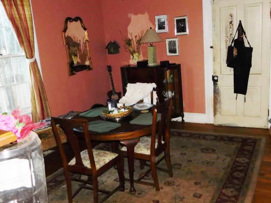 1/2 house is all yours. This pic shows the dining room portion of this large space that is divided only by a freestanding brick fireplace. A bed is on each side. The doorway shown leads into the kitchen which you would have easy access to