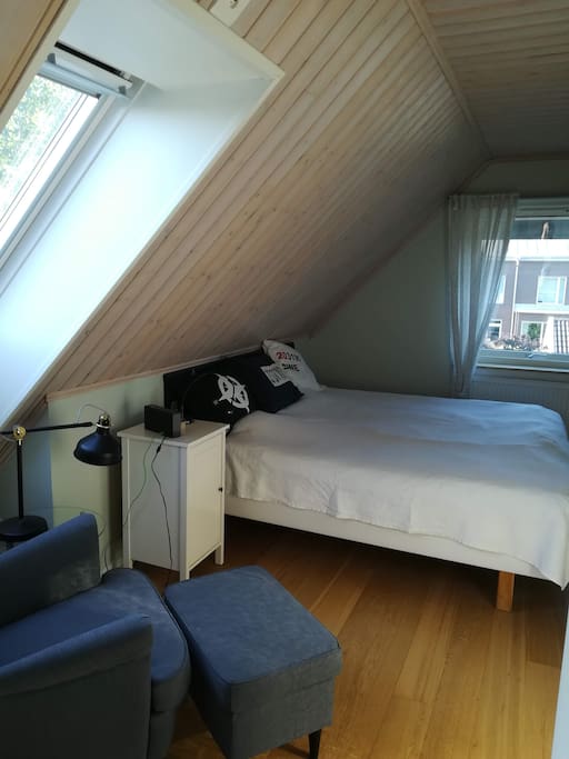 Eget låsbart sovrum med stor dubbelsäng, takfönster och en bekväm läsfåtölj