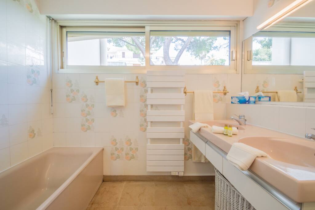 Full bathroom with bathtub, double sink, towel warmer