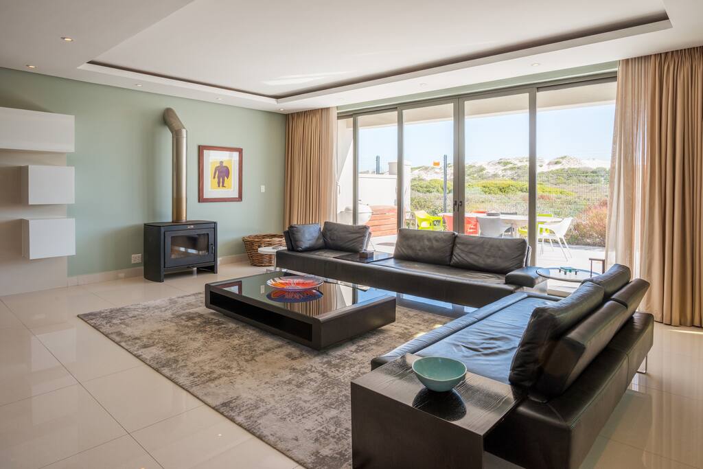 Downstairs living room with fireplace opening to outside entertainment and pool area with retractable sliding doors