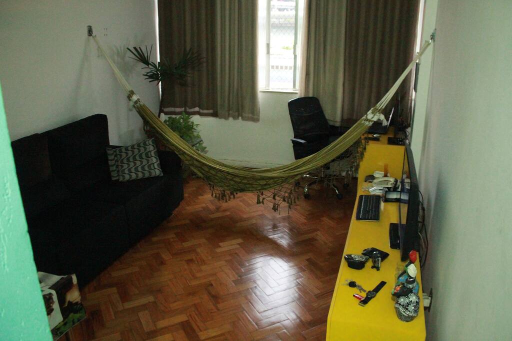 A sala possuí rede, um sofá cama, home theater e espaço para jantar e trabalhar.