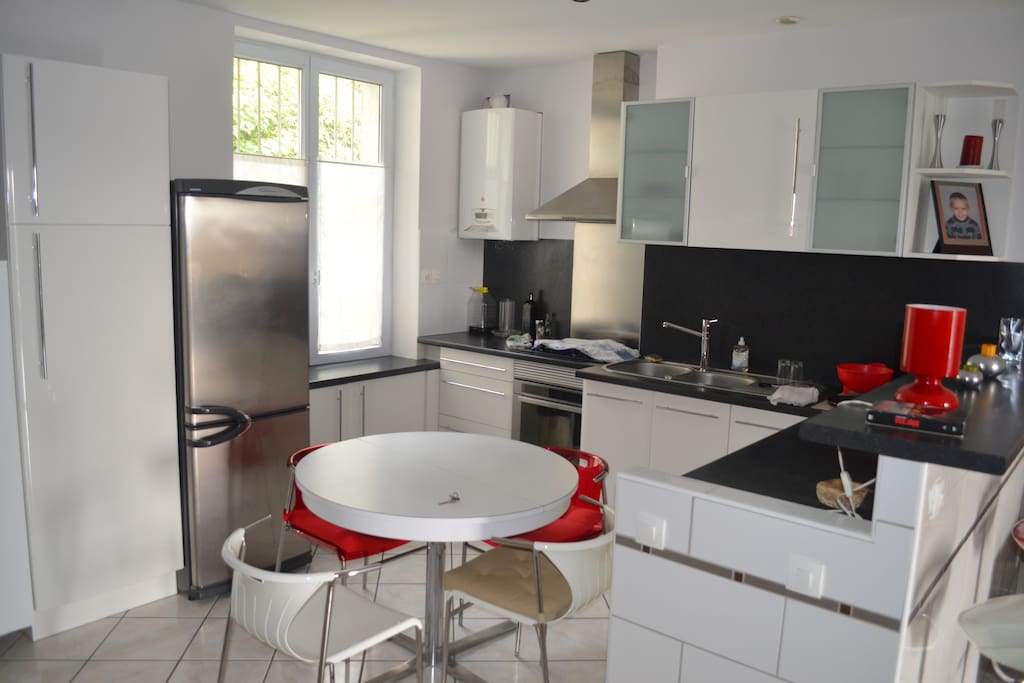 Cuisine américaine dans le salon (le tout = 30 m2). Plaque, four, frigo, table pour quatre. Bar.