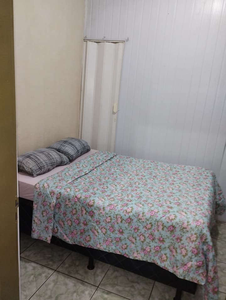 Двойна спалня с спално бельо и вентилатор.