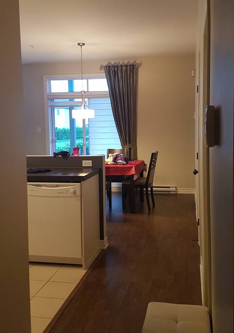 Intérieur depuis la porte d'entrée, la perspective montre la cuisine, la salle à manger et tout au fond, le petit patio. À droite se trouvent les 2 chambres et la salle de bain.